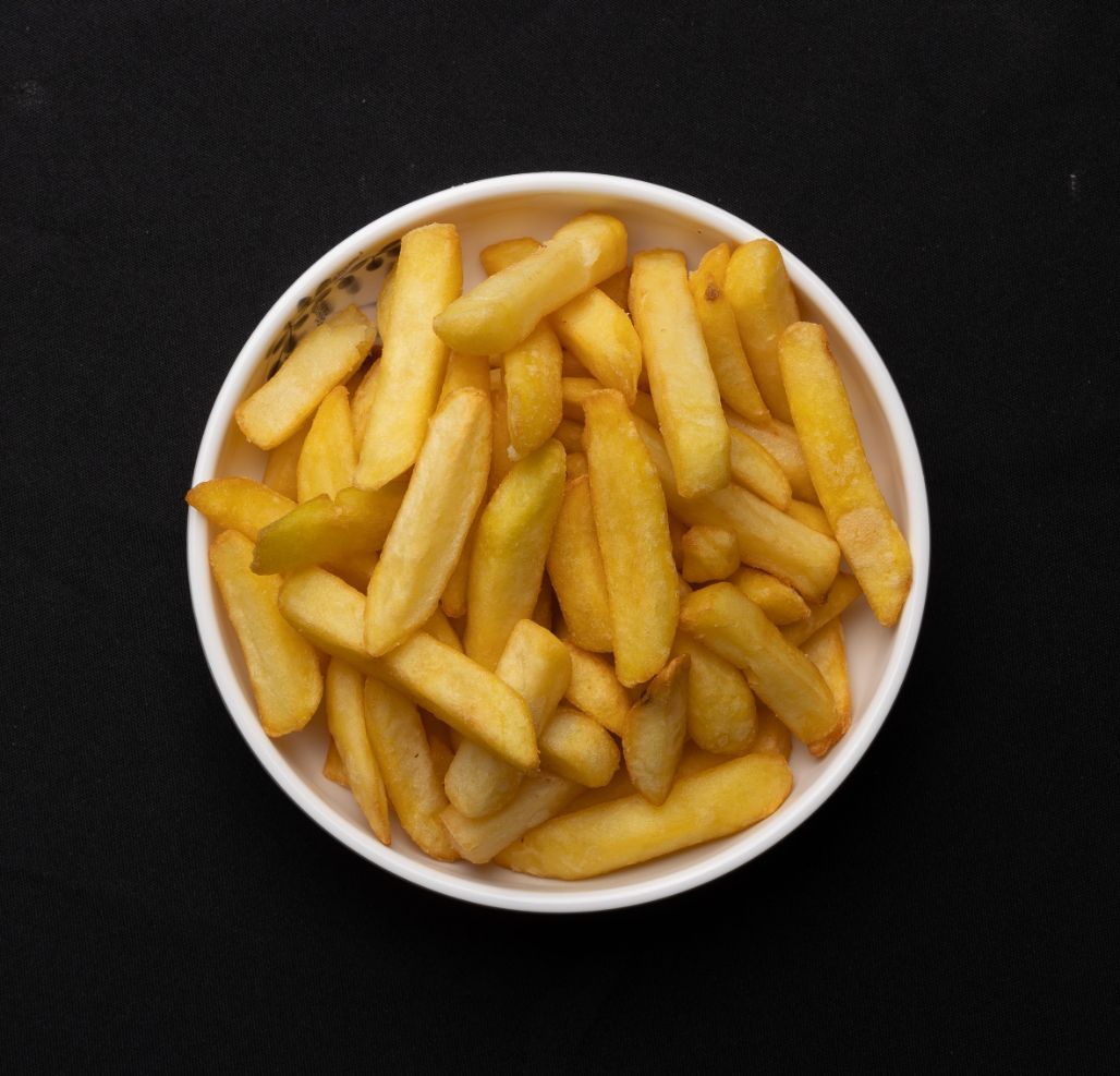 A bowl of french fries on a black background