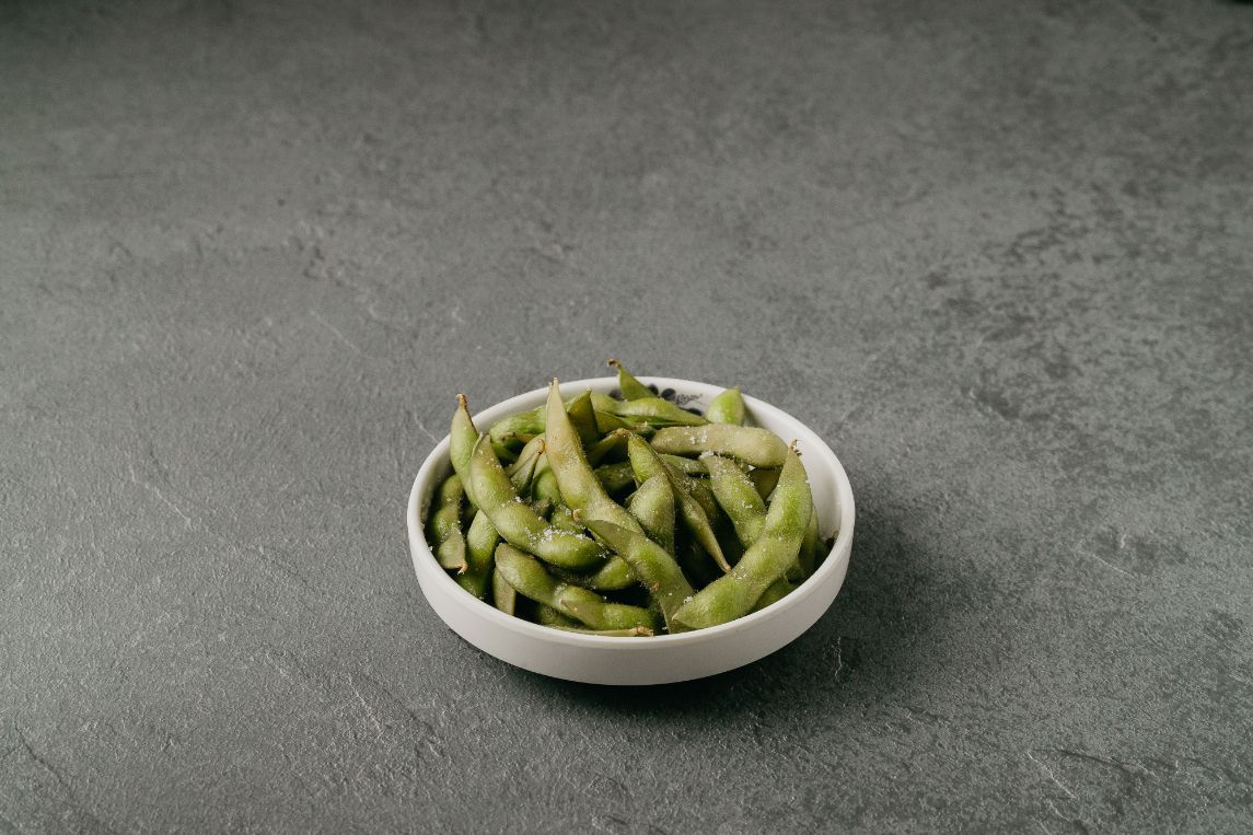 A white bowl filled with green beans on a table.