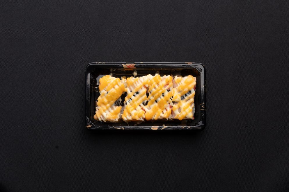 A black tray filled with food on a black surface.