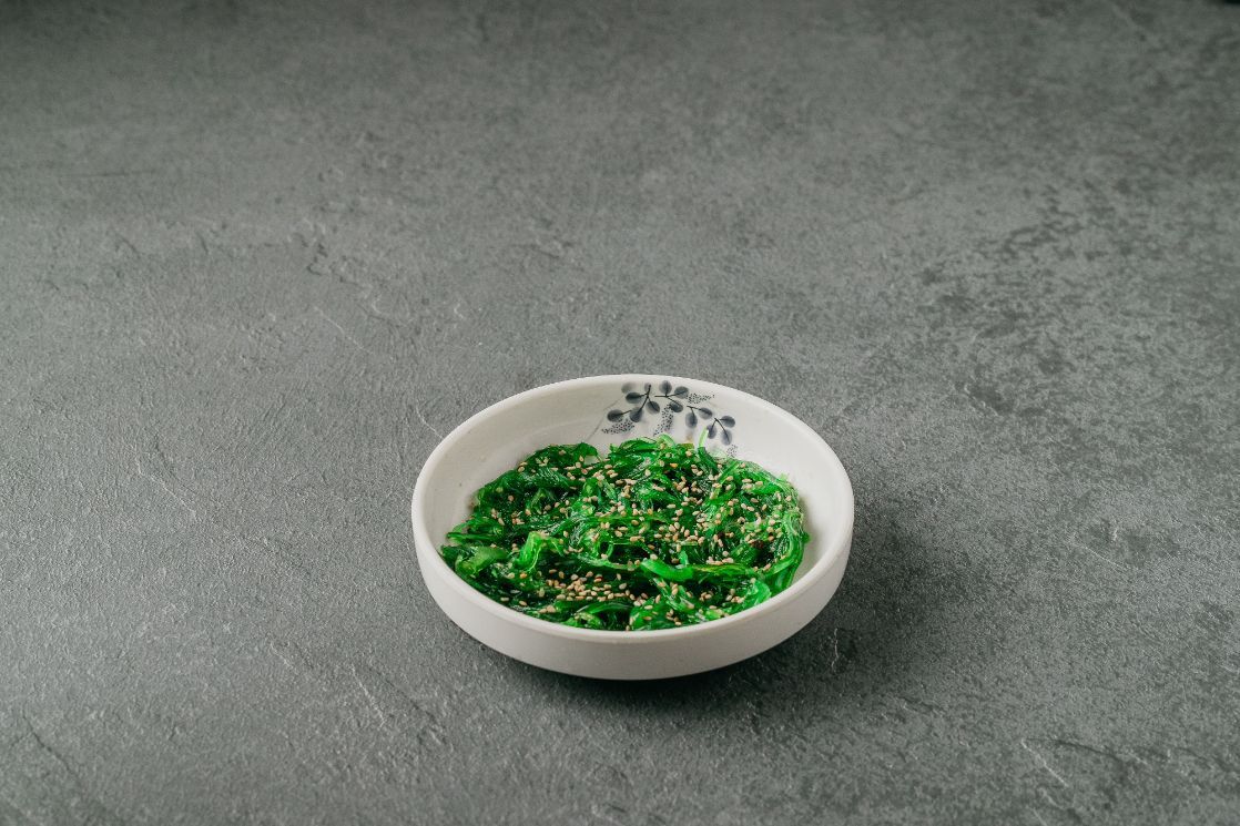 A small white bowl filled with green vegetables on a table.