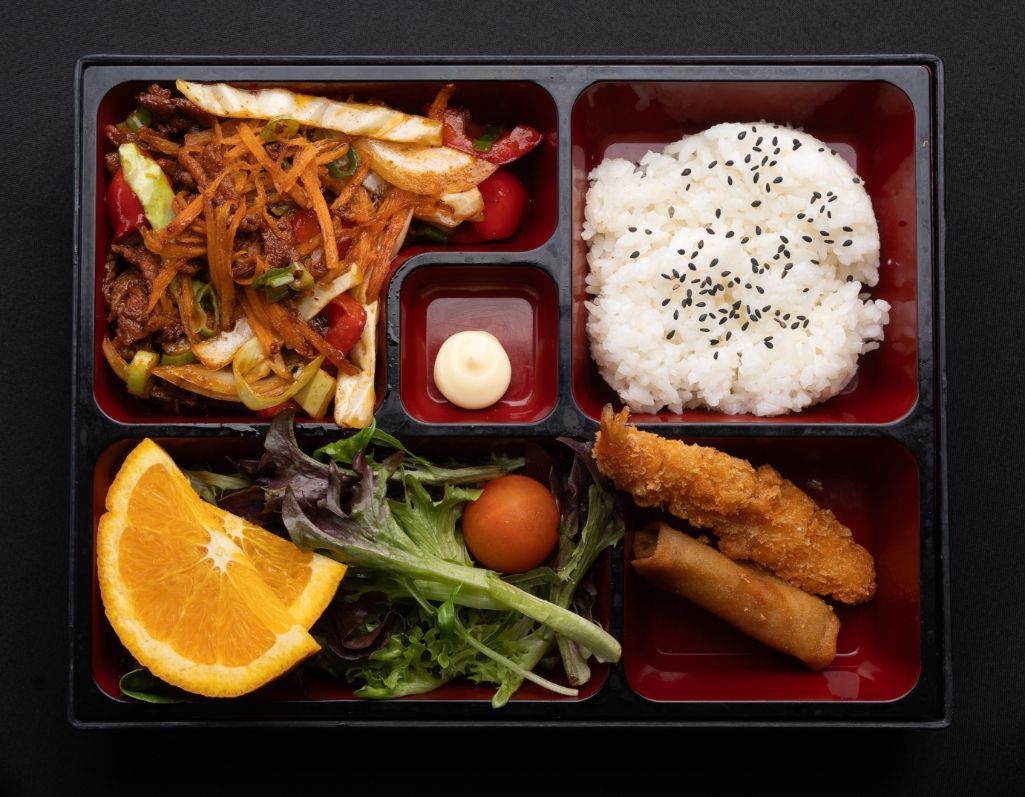 A bento box filled with rice , vegetables , and fried food.