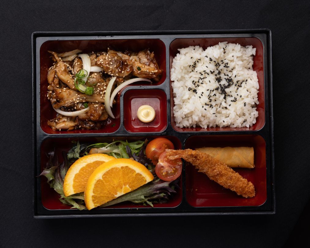 A bento box filled with rice , vegetables , and fried food.