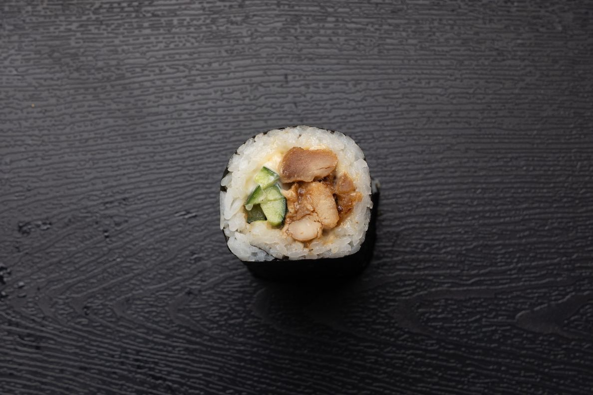 A close up of a sushi roll on a black surface.