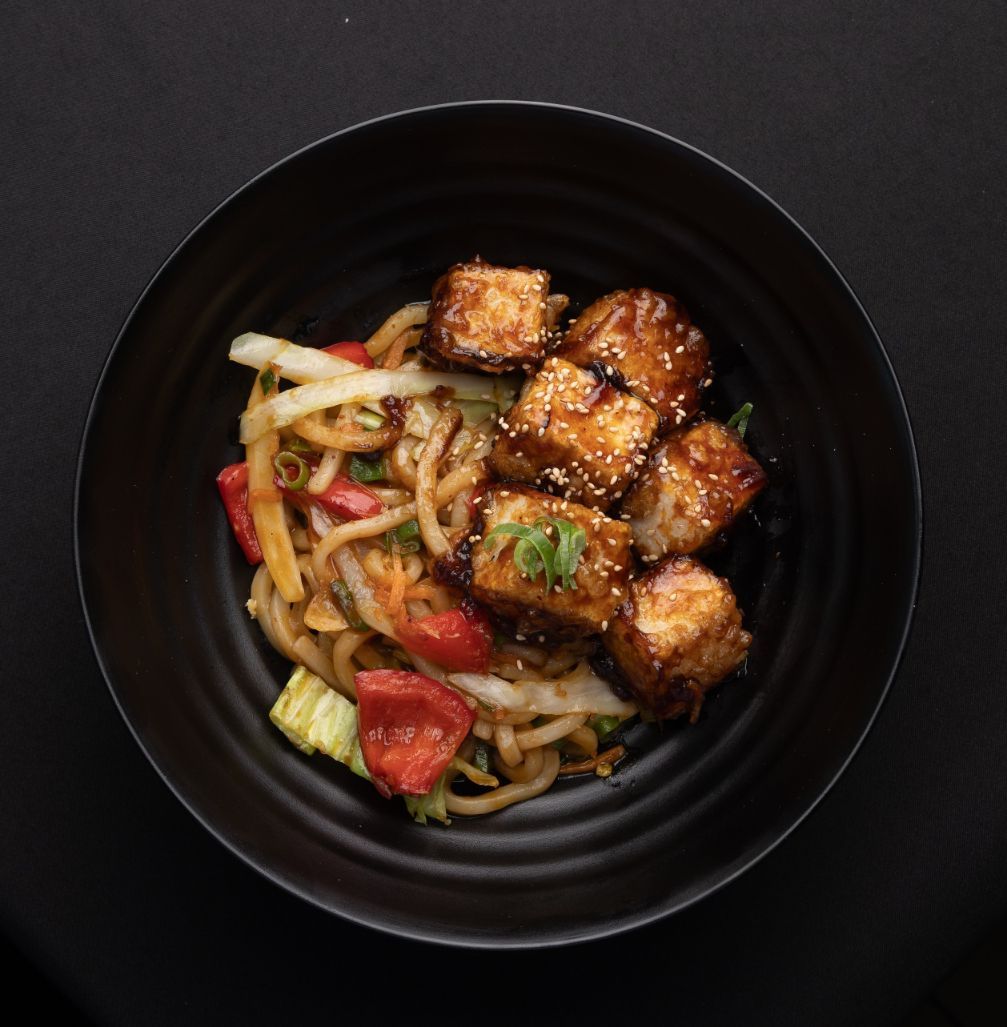 A black bowl filled with noodles and meat on a table