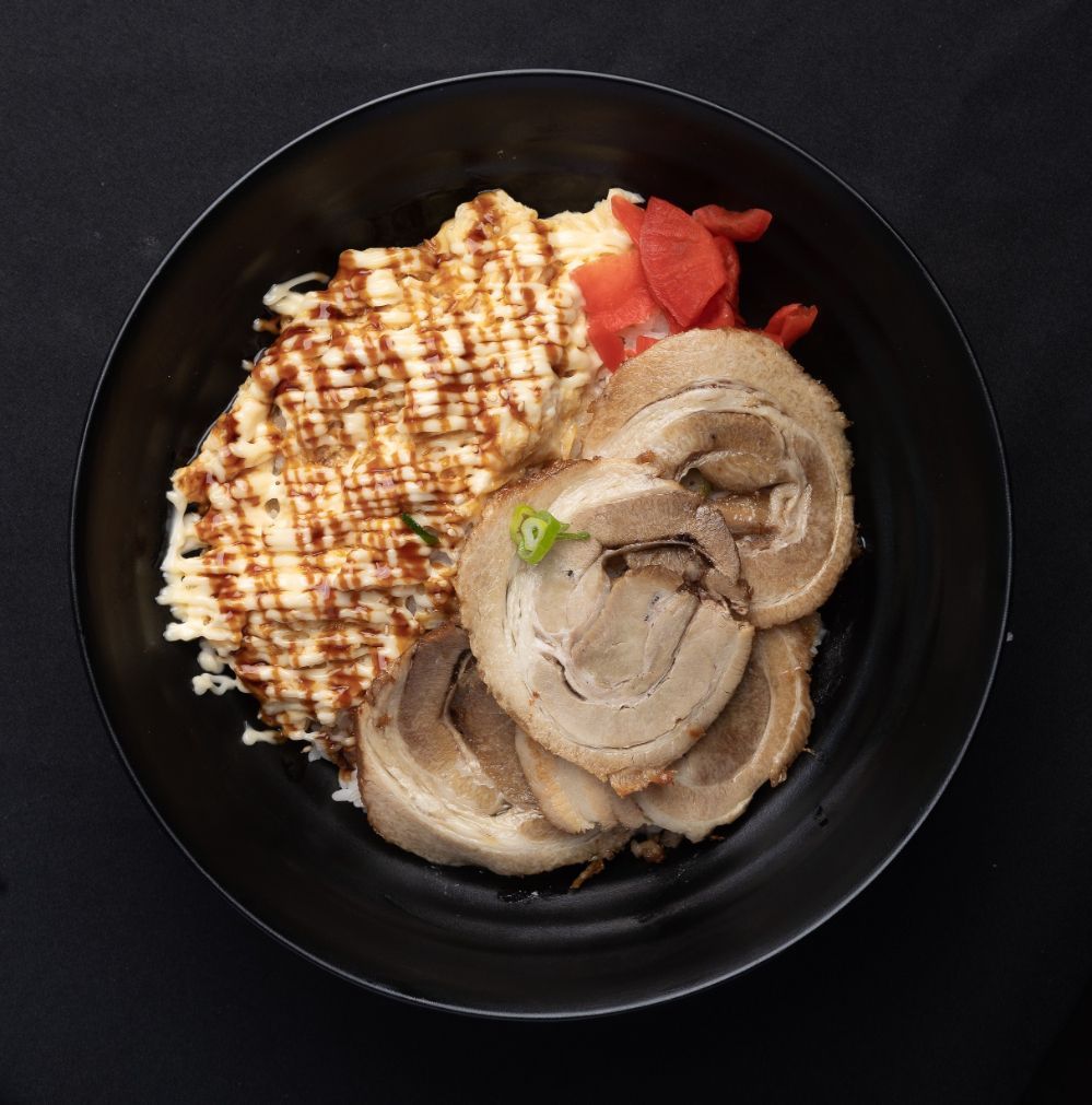 A black bowl filled with meat and rice on a table.