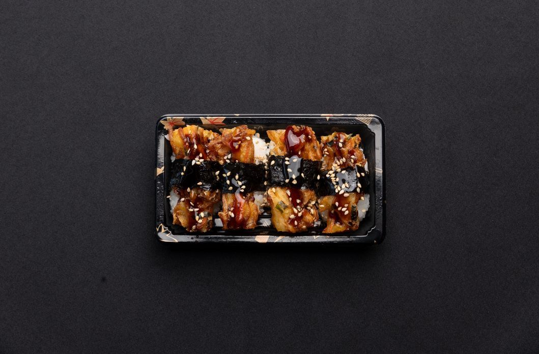 A black plastic container filled with food on a black table.