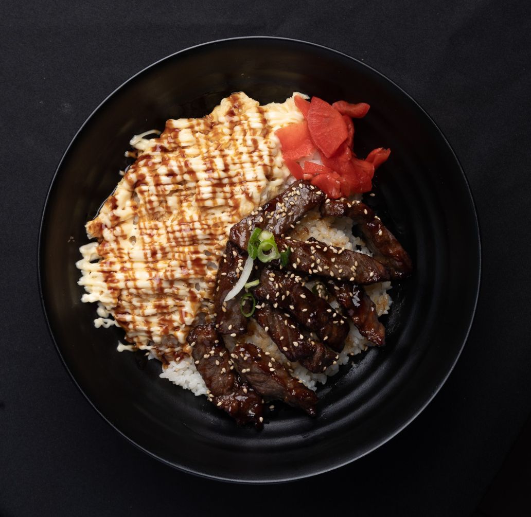 A black bowl filled with meat and rice on a table