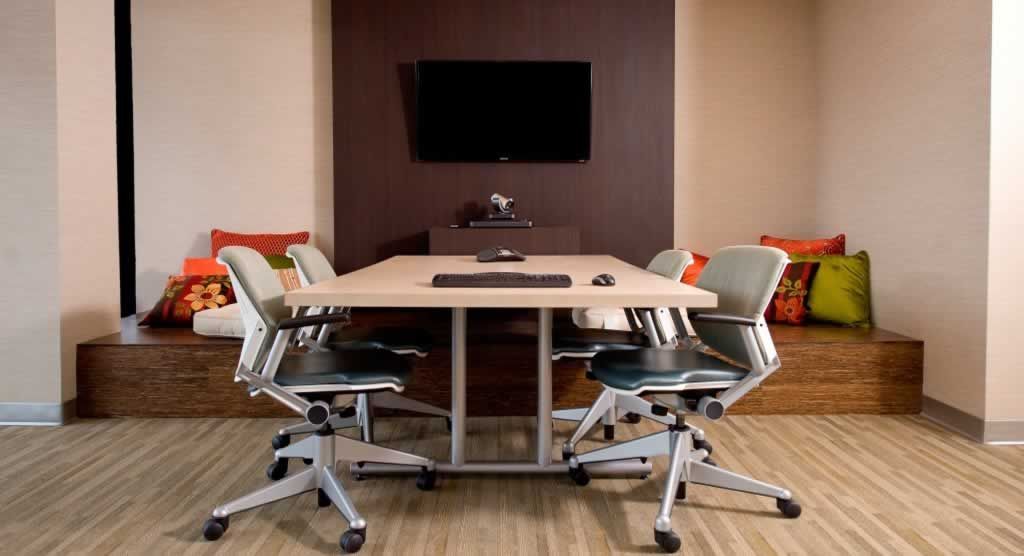 A conference room with a table and chairs and a flat screen tv.