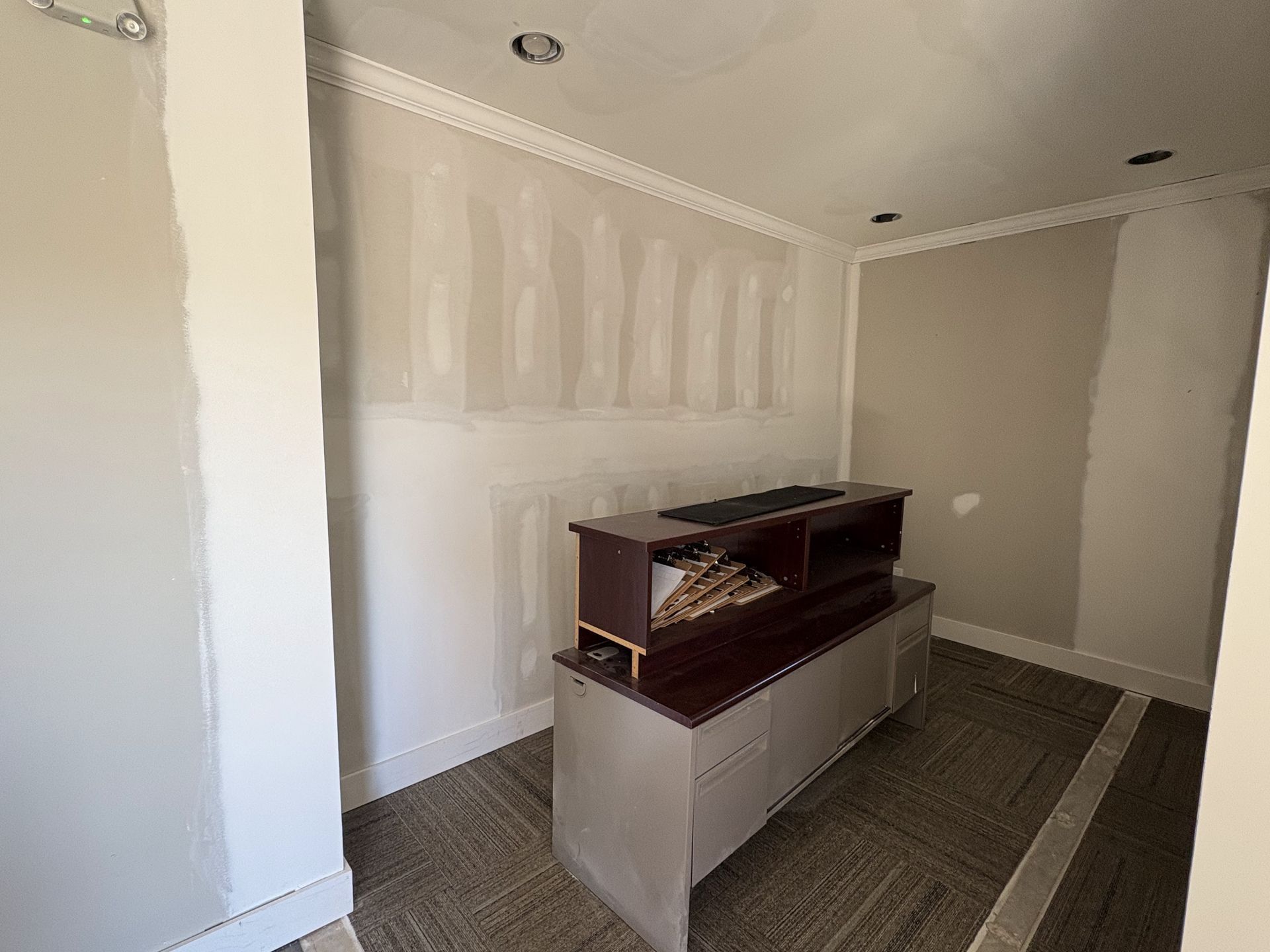 Small unfinished room with white drywall, recessed lights, and a counter or cabinet in the center.