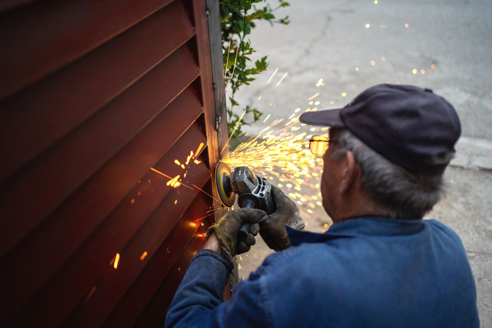 Man Using Grinder to Cut a Piece of Metal — Denison, TX — North Central Door and Gate