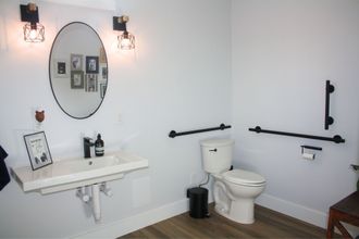 A bathroom with a toilet , sink and mirror.