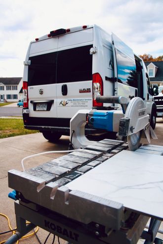 A white van is parked next to a kobalt table saw