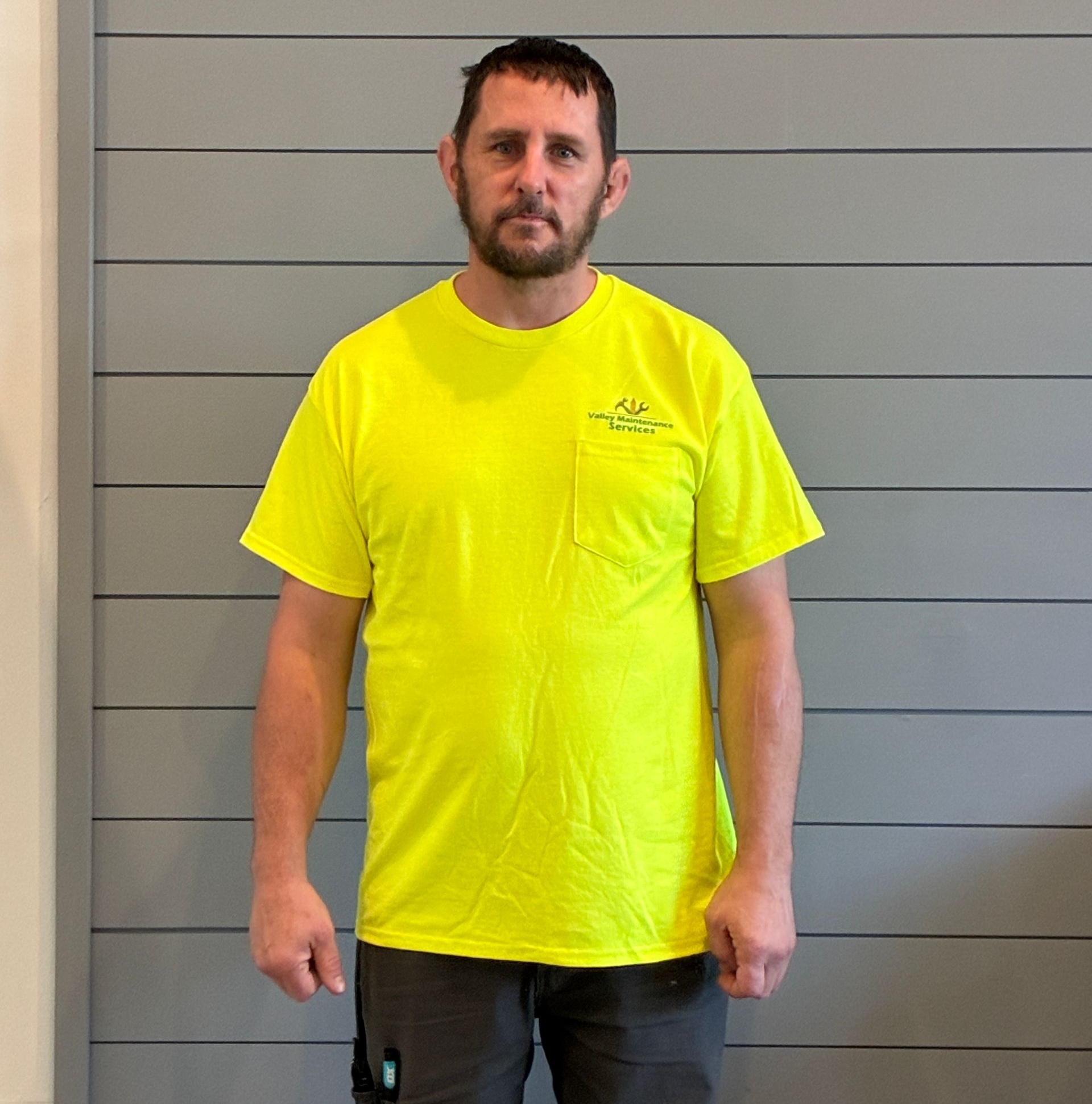 Man in a neon yellow T-shirt standing against a gray wall