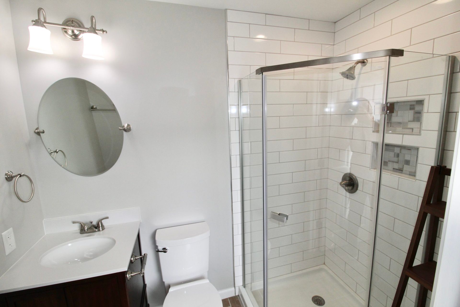 A bathroom with a toilet , sink , shower and mirror.