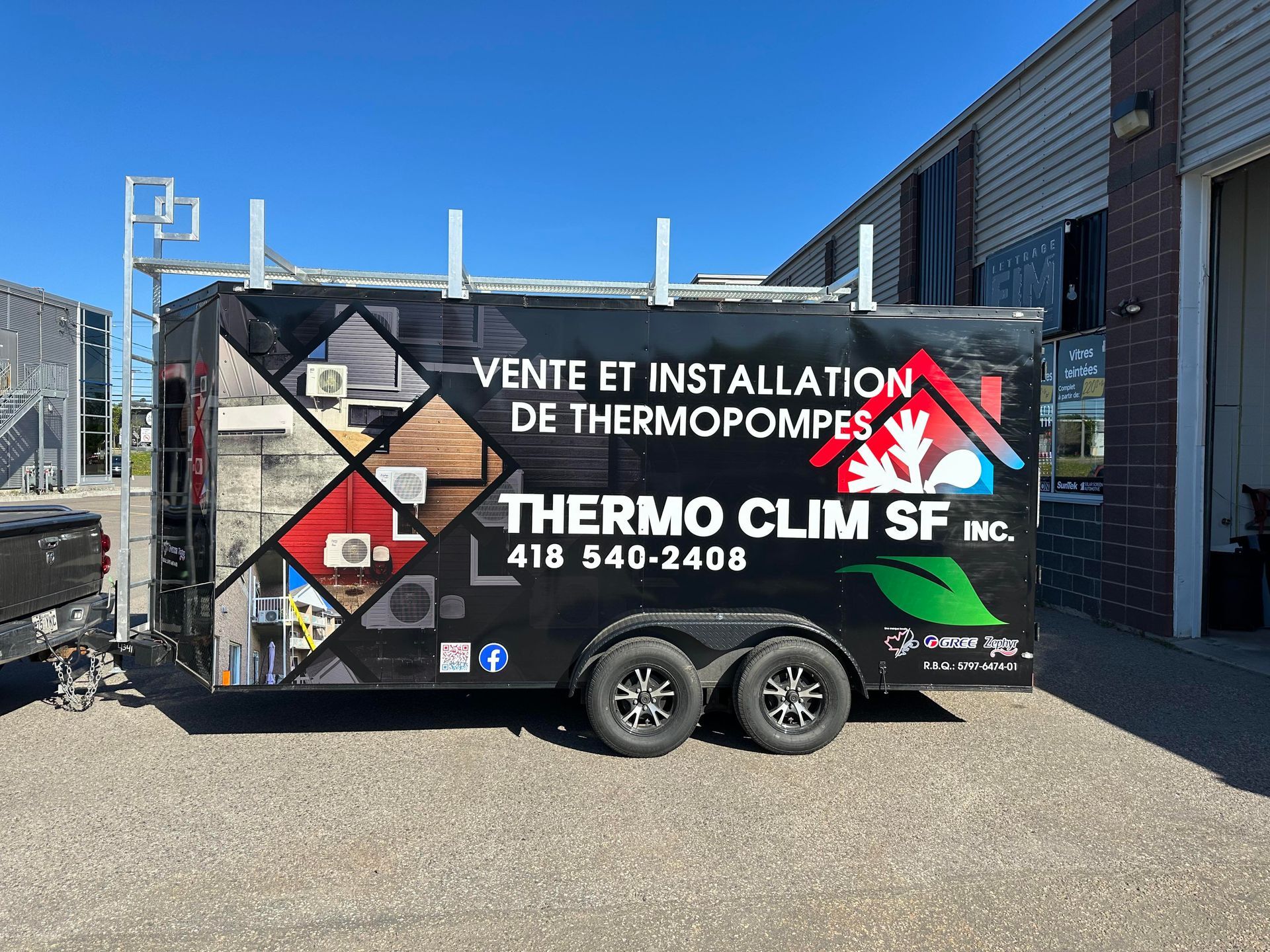 Une remorque pour thermo clim sf inc. est garé devant un immeuble.