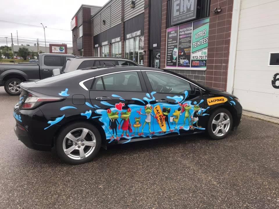 Une voiture noire avec une peinture colorée sur le côté est garée devant un immeuble.