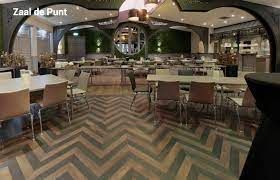Lege restaurantzaal met tafels en stoelen, een vloer met patroon en een gewelfd plafond tonen de prachtige evenementenzaal in De Raayberg Zalencomplex, Bergen op Zoom.