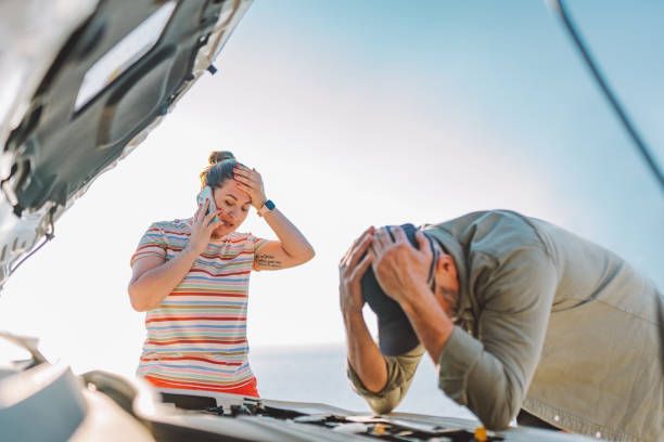 A Man and a Woman Are Standing Next to a Broken Down Car — Pearl, MS — Hall’s Towing Service
