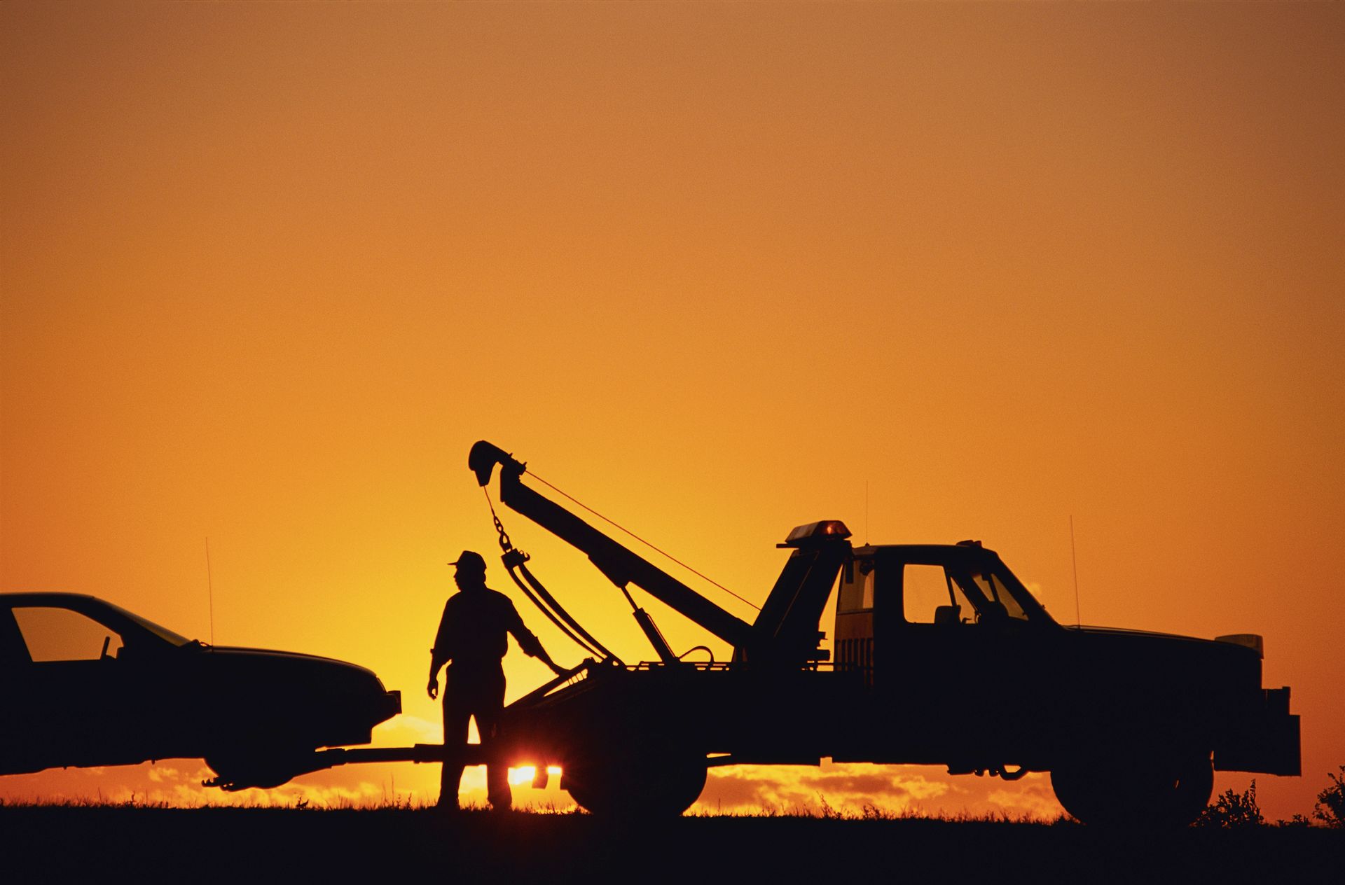 A Tow Truck Is Towing a Car at Sunset — Pearl, MS — Hall’s Towing Service