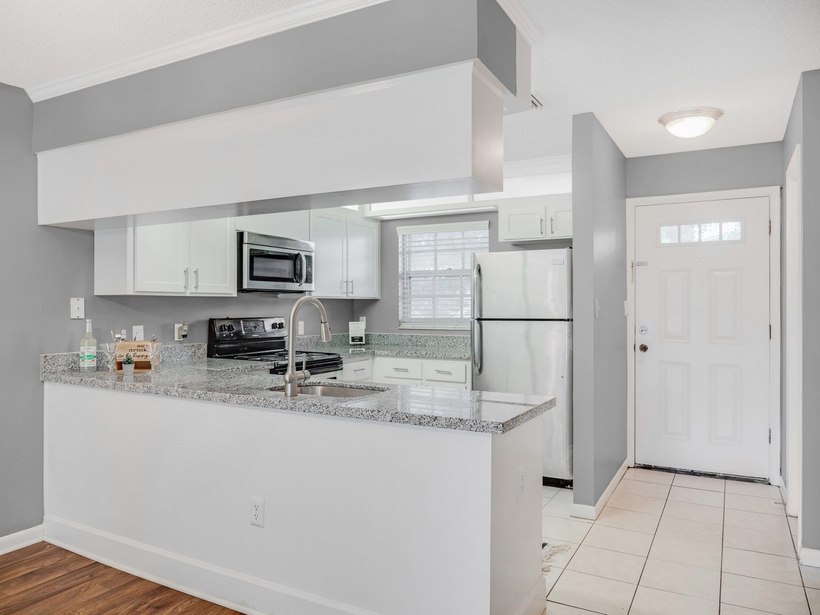 A kitchen with white cabinets , granite counter tops , stainless steel appliances and a refrigerator at Veridian of Melbourne Townhome Apartments in Melbourne, FL.
