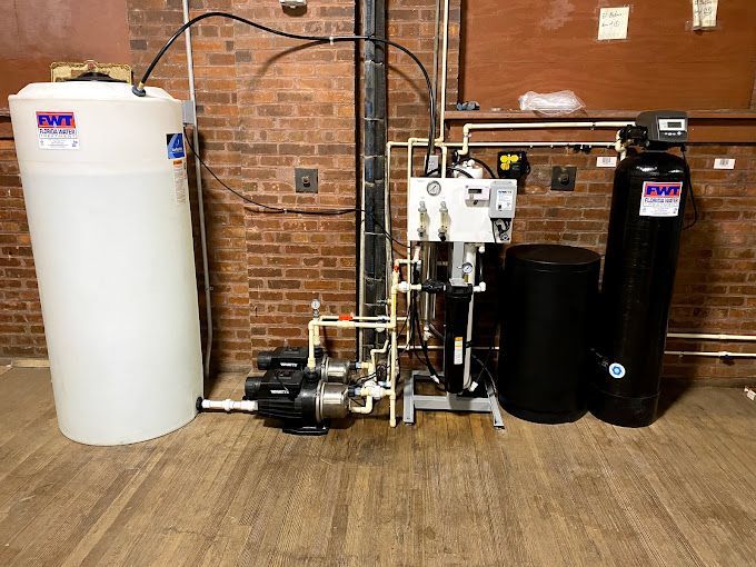 A water treatment system is installed in a basement next to a brick wall.