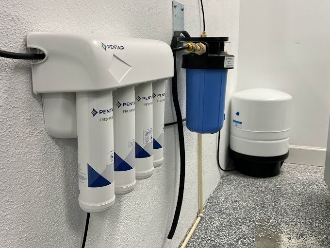 A water filter is hanging on a wall next to a water tank.