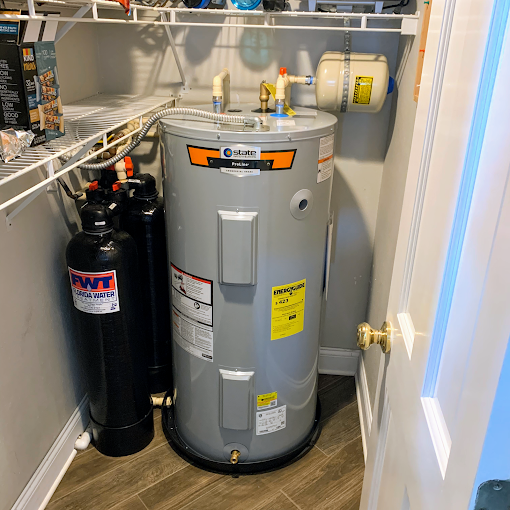 A water heater is sitting in a closet next to a door.