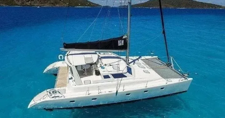 A group of people are sitting on the back of a sailboat in the ocean.