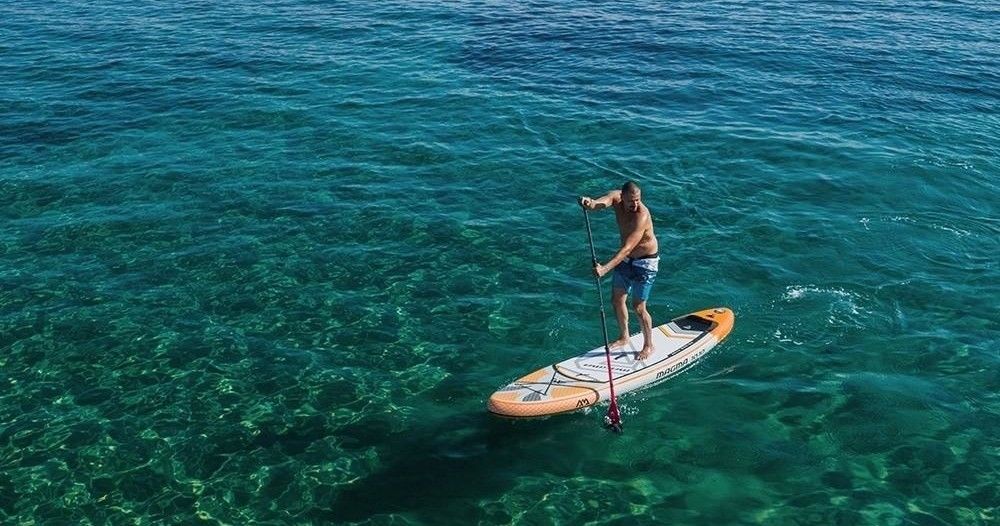 A woman in a bikini is standing on a paddle board in the ocean.