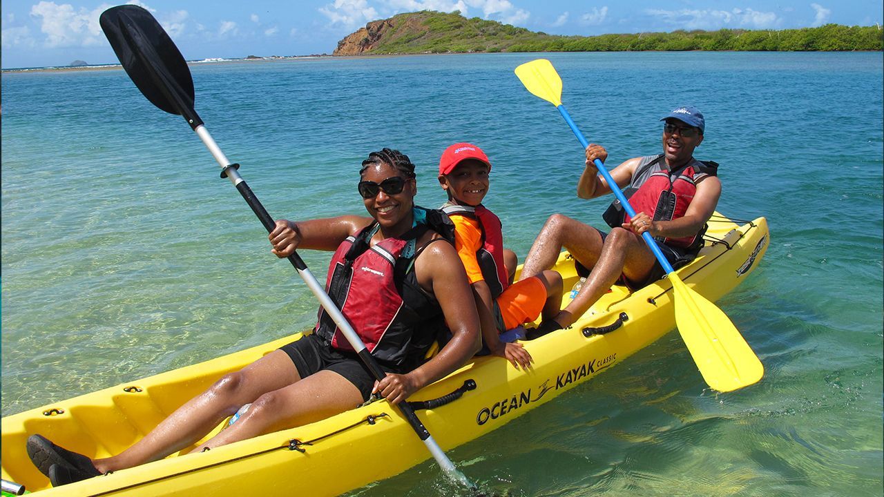 Three people are in a yellow kayak in the water.