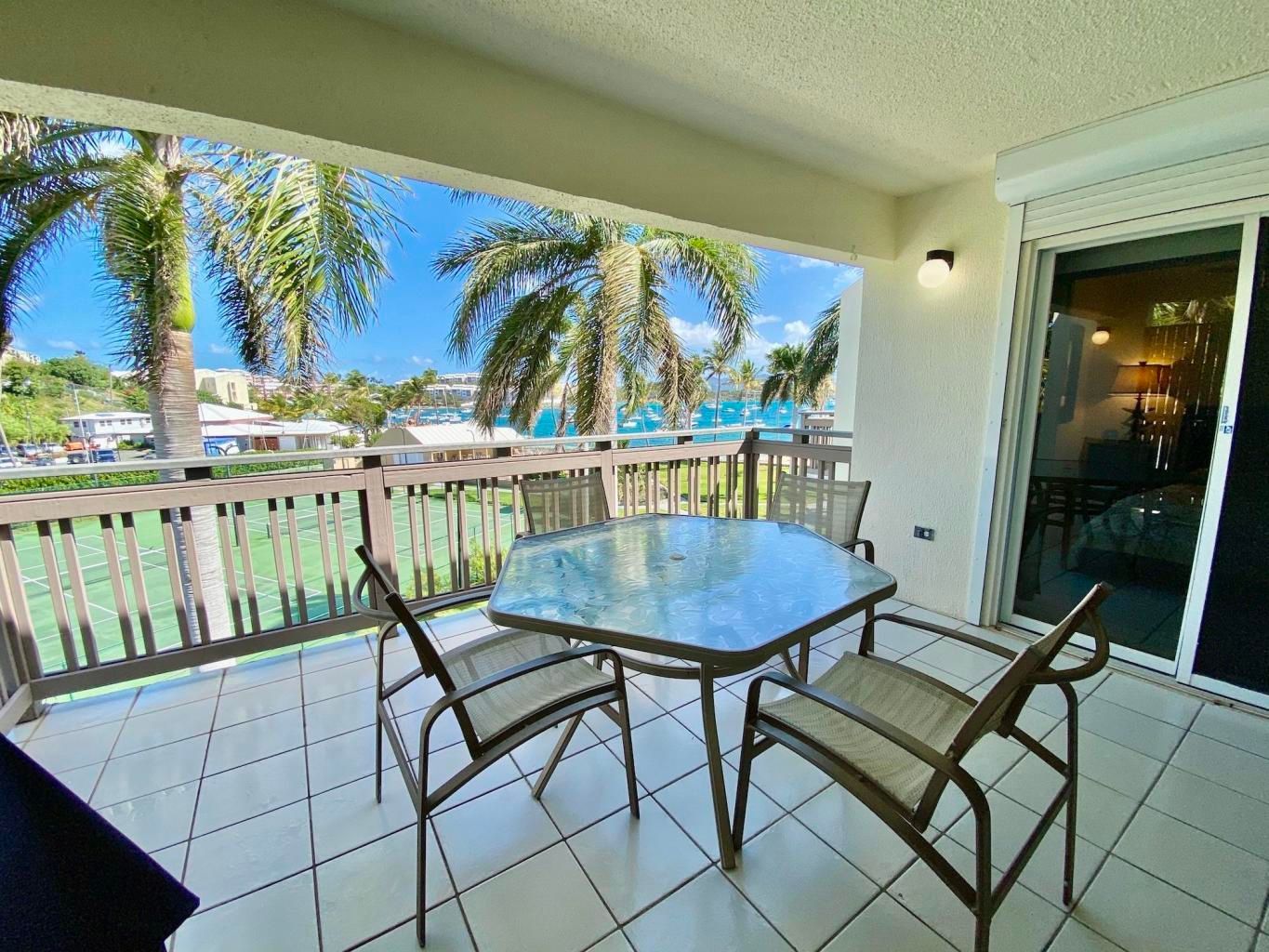 There is a table and chairs on the balcony with a view of the ocean.