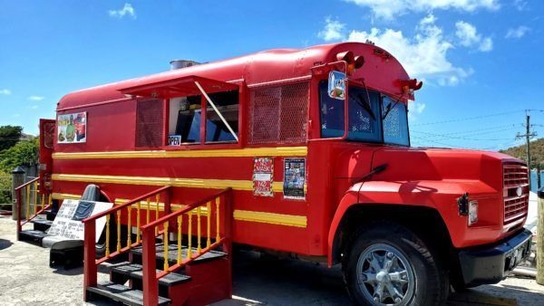 A red and yellow food truck is parked in a parking lot.