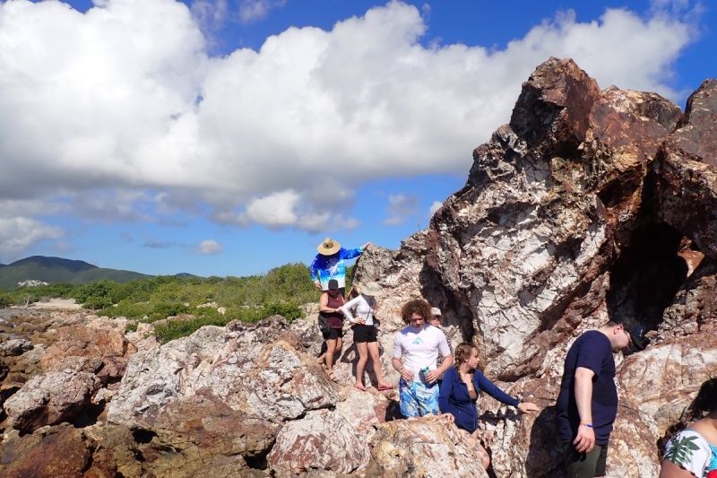 A group of people are standing on top of a rocky hill.