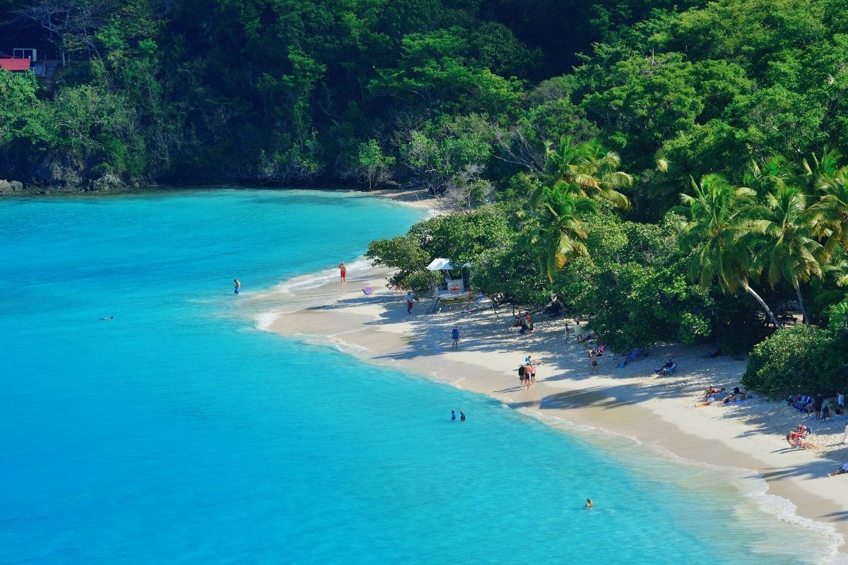 An aerial view of a tropical beach surrounded by trees and water.