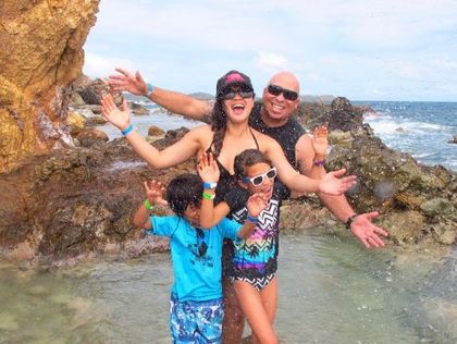 A group of people are swimming in the water holding shells and giving a thumbs up.
