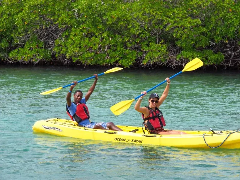 Two people are paddling a yellow kayak in the water.