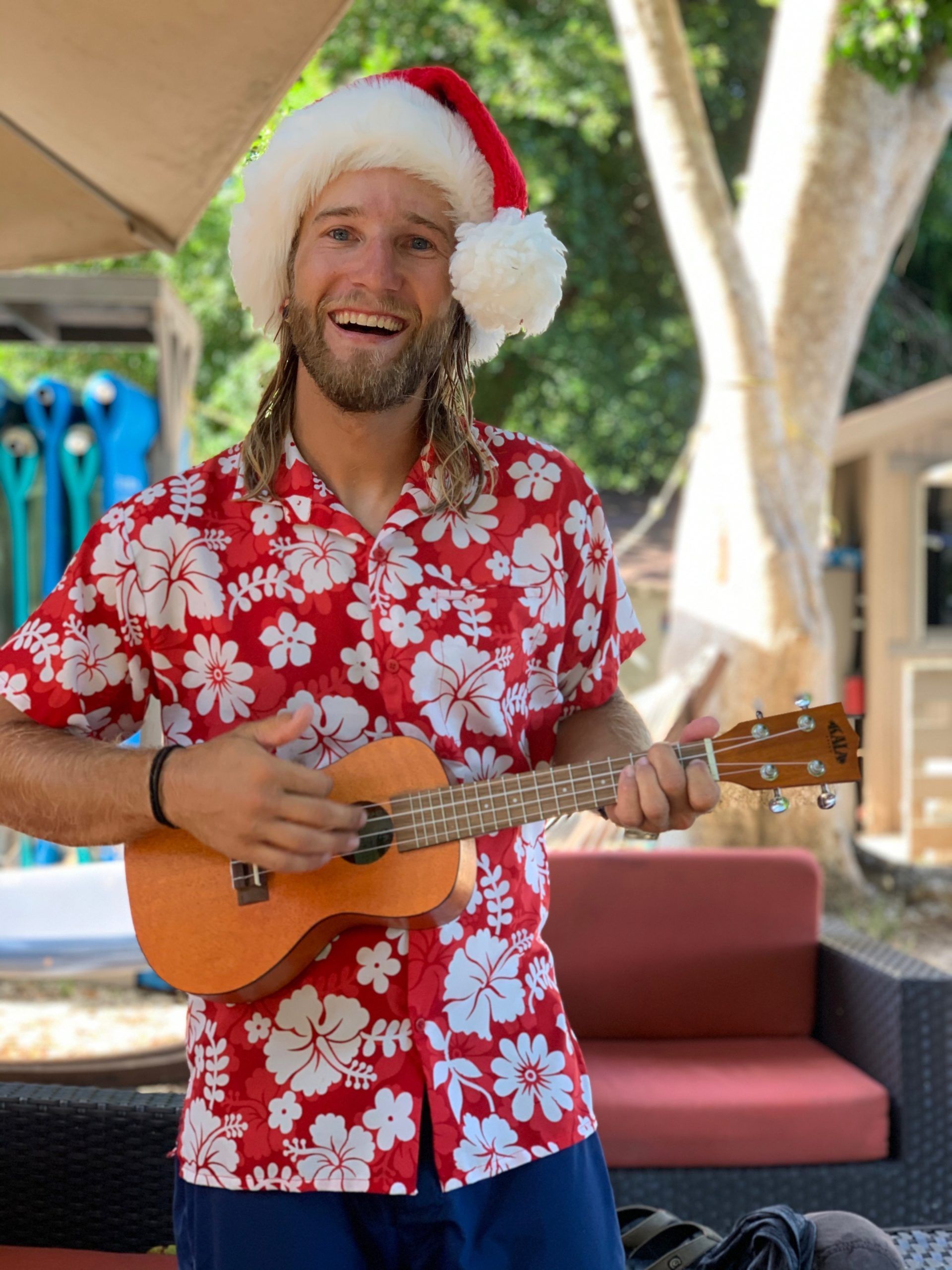 A man wearing a santa hat is playing an ukulele