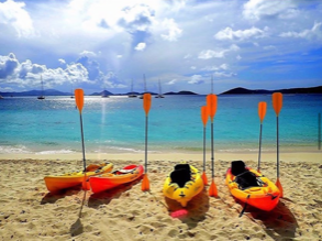 Three kayaks are lined up on a sandy beach
