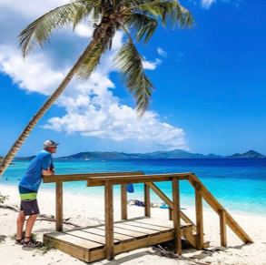 A man standing on a beach with stairs leading to the ocean