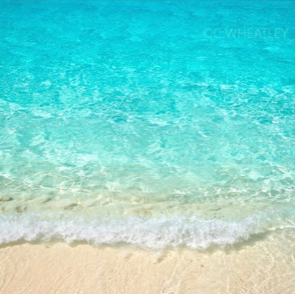 A close up of a beach with waves crashing on the sand.