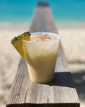 A pineapple drink in a plastic cup on a wooden bench