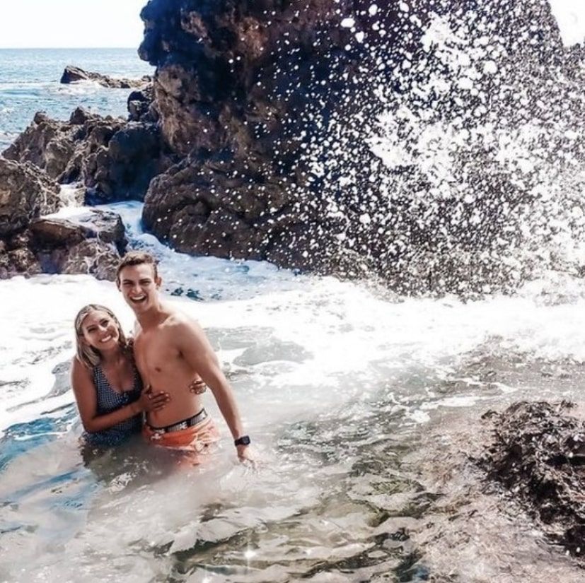 A man and a woman are standing in the ocean