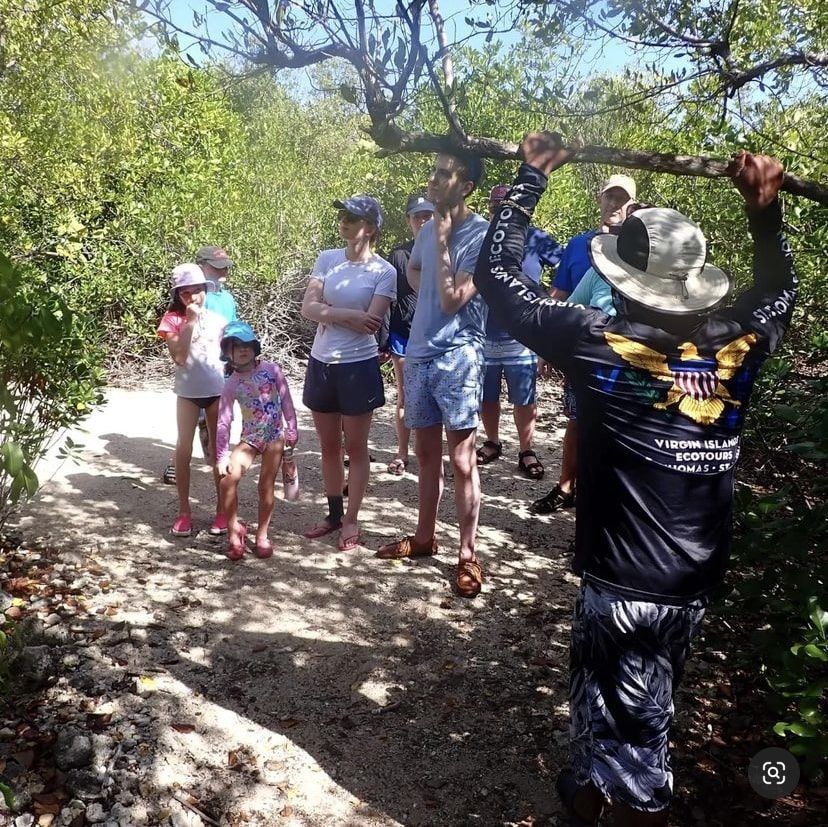 A group of people standing on a path with a man holding a stick