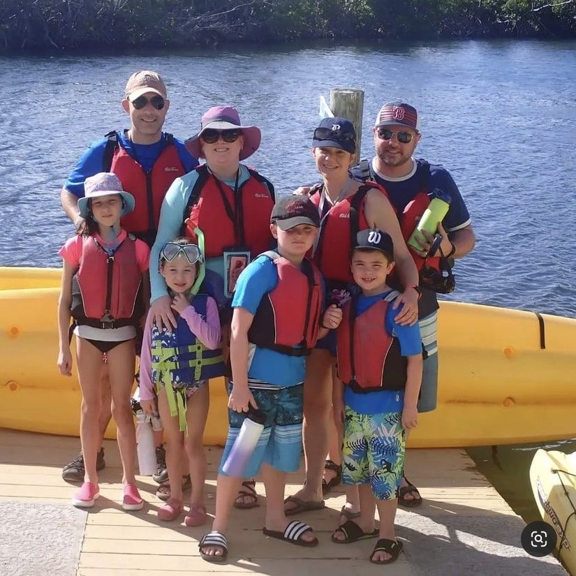 A group of people posing for a picture in front of a body of water