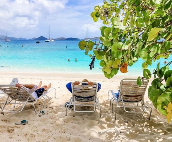 People are laying in chairs on the beach looking at the ocean