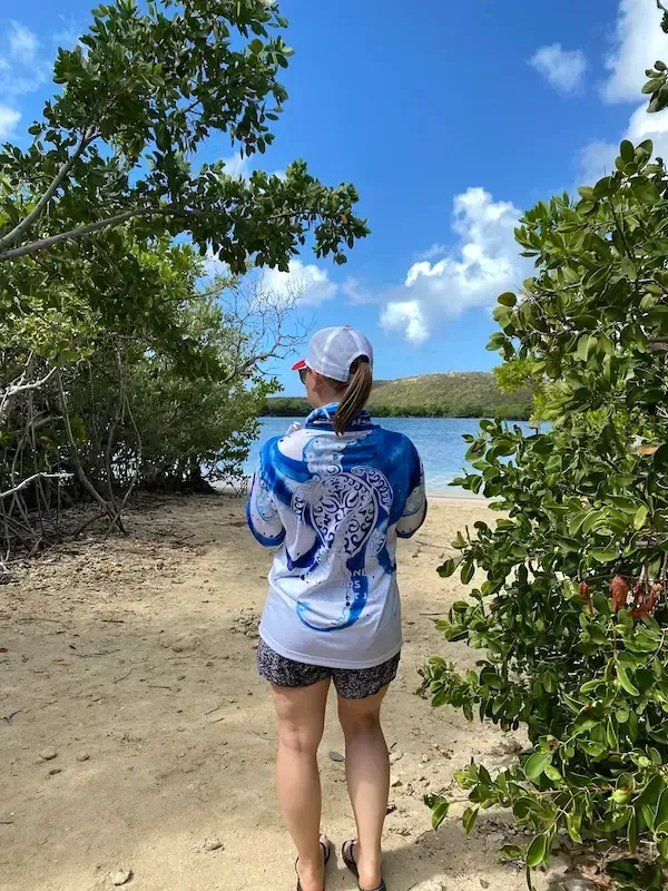 A woman is standing on a beach looking at the water.