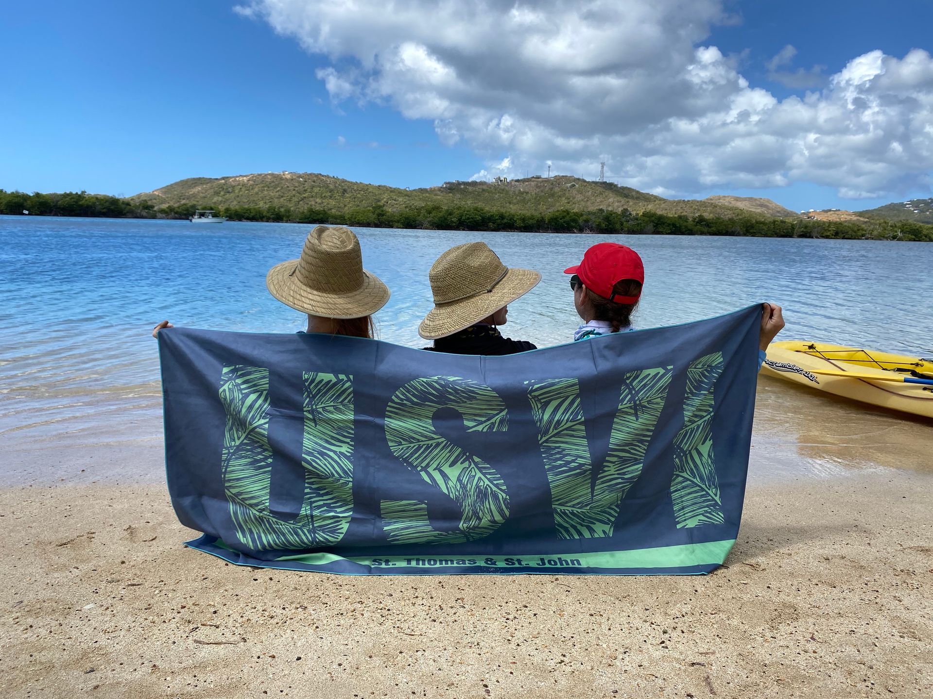 Two people sitting on a beach holding a towel that says usv