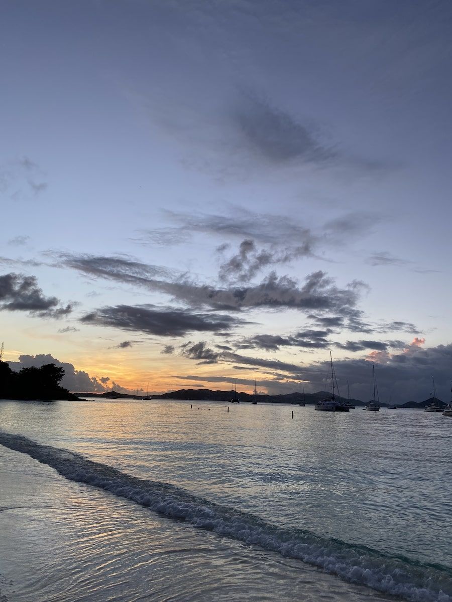 A sunset over a body of water with boats in the distance.