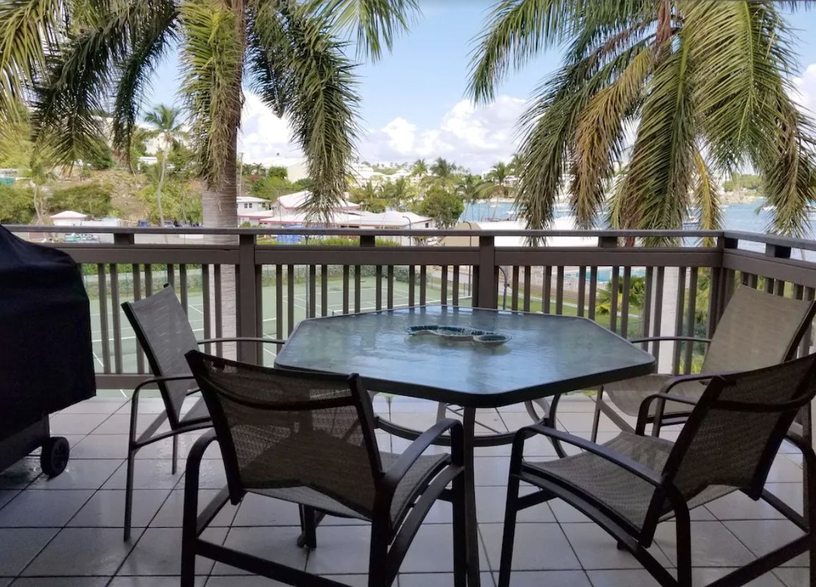 A table and chairs on a balcony overlooking a body of water.