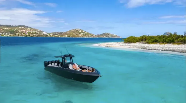 A boat is floating on top of a body of water near a small island.